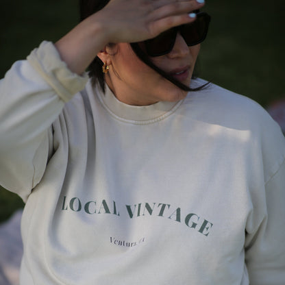 Person wearing a white hoodie with 'LOCAL VINTAGE' text, blurred background