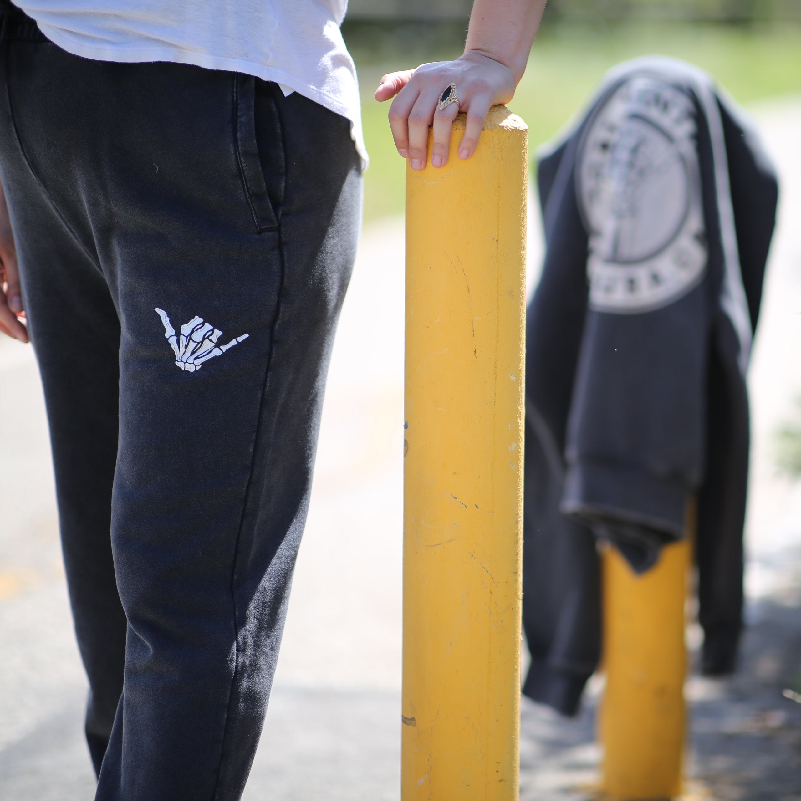 Person wearing black pants with a white logo, standing next to a yellow pole and fire hydrant.