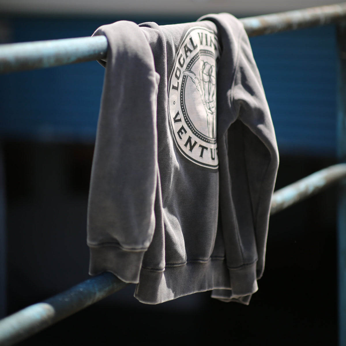 Folded gray sweatshirt with a logo on a metal chair against a blurred background